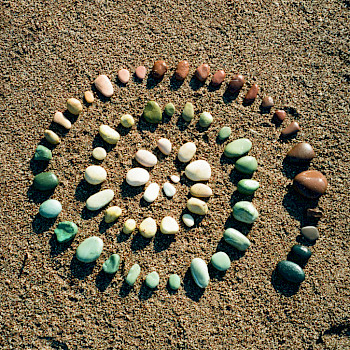 Spirale aus bunten Steinen auf Sand