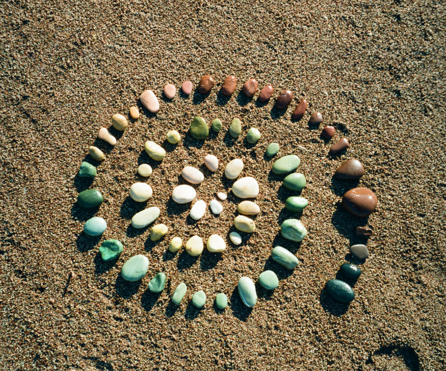 Spirale aus bunten Steinen auf Sand